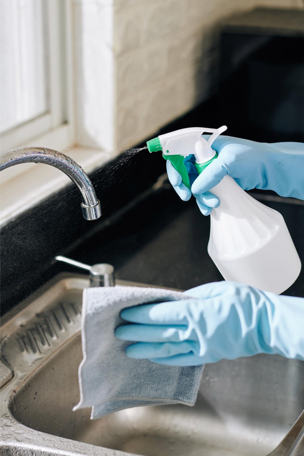 Hands cleaning sink with rag and spray bottle