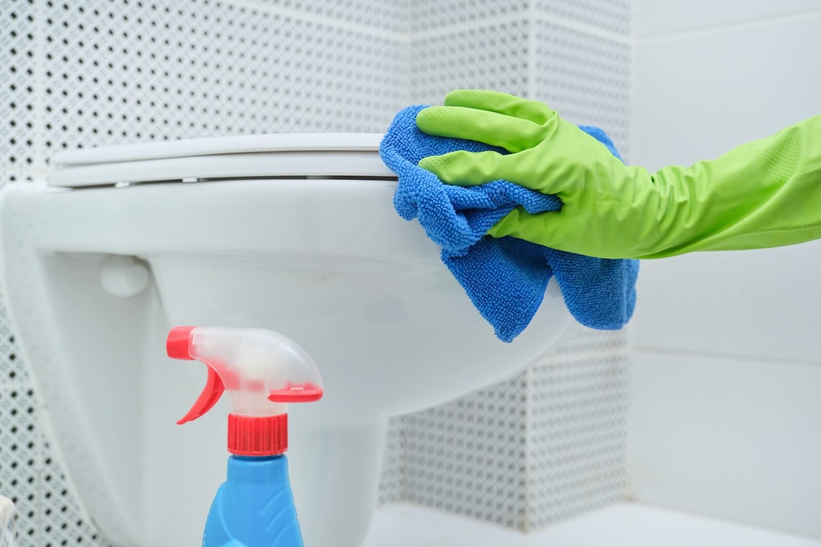 Gloved hand cleaning toilet with rag
