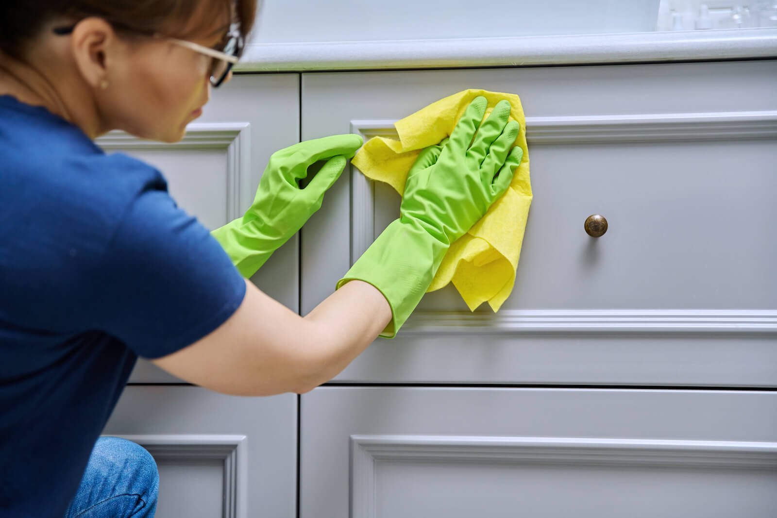 Woman wiping cabinets with rag